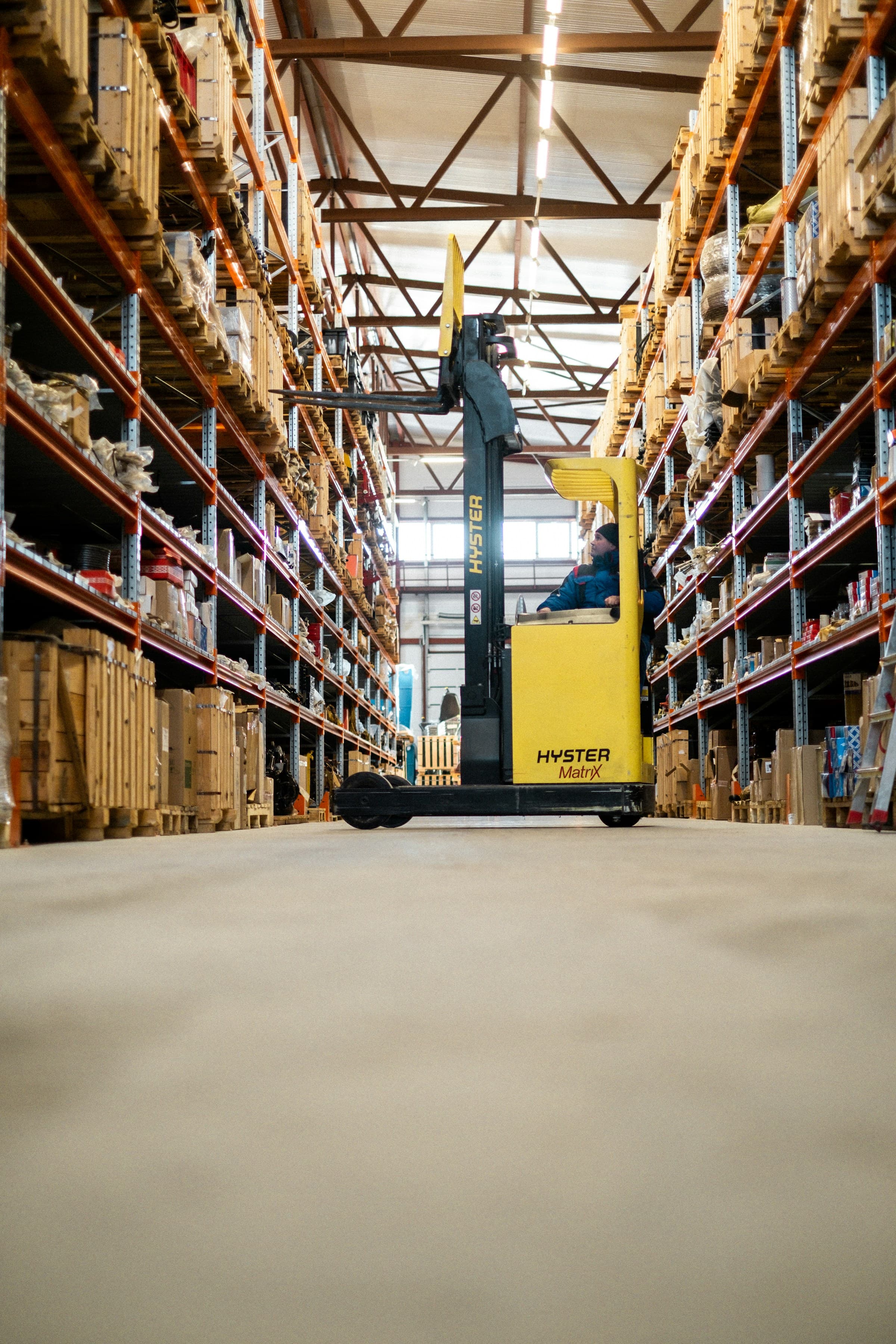 A warehouse aisle with a forklift between tall racks